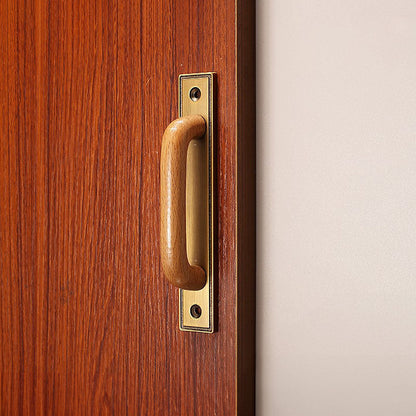 Wood cabinet pull with a rectangular metal backplate, shown clearly installed on cabinetry in context