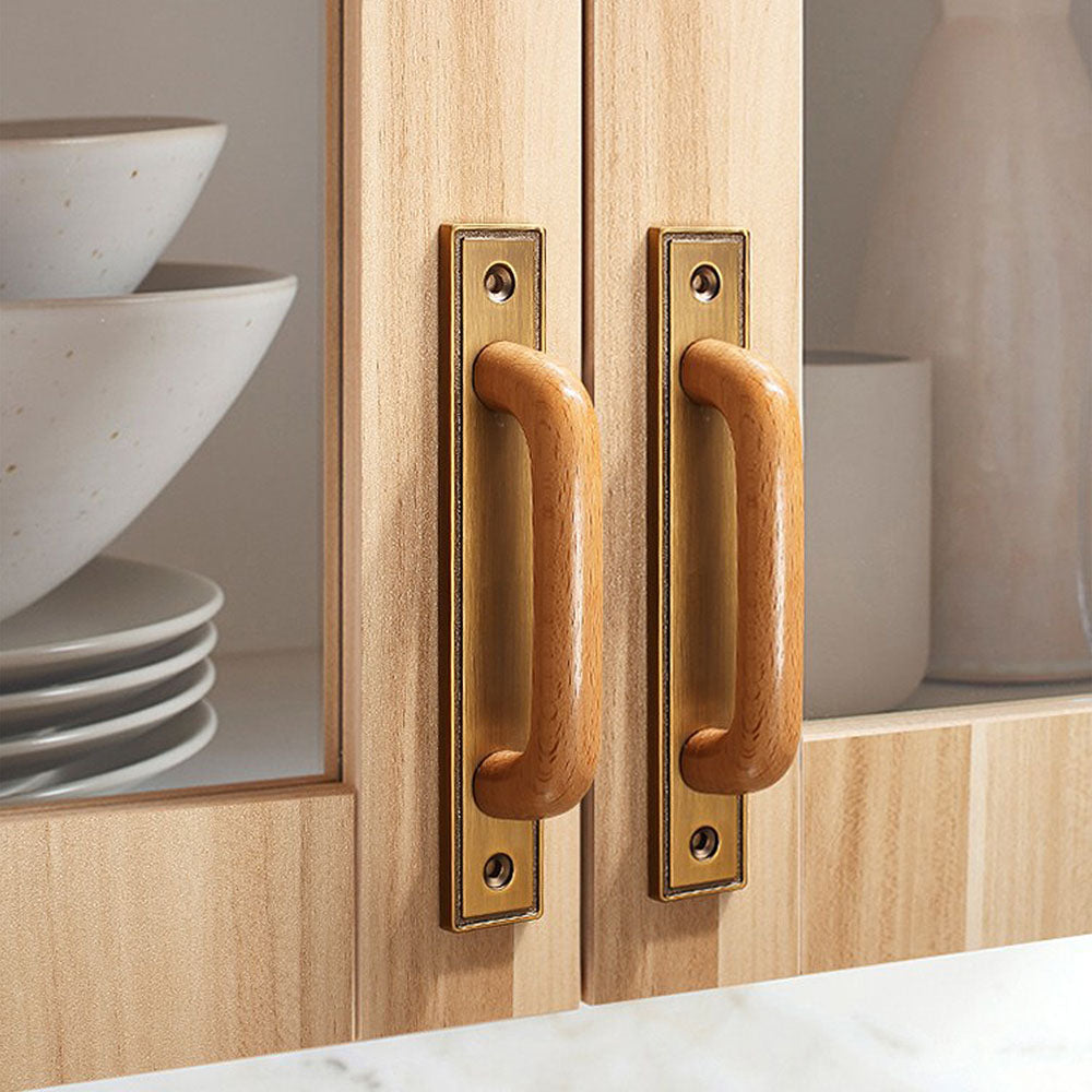 Wood cabinet pull with a rectangular metal backplate, pictured in one view installed on cabinetry in context