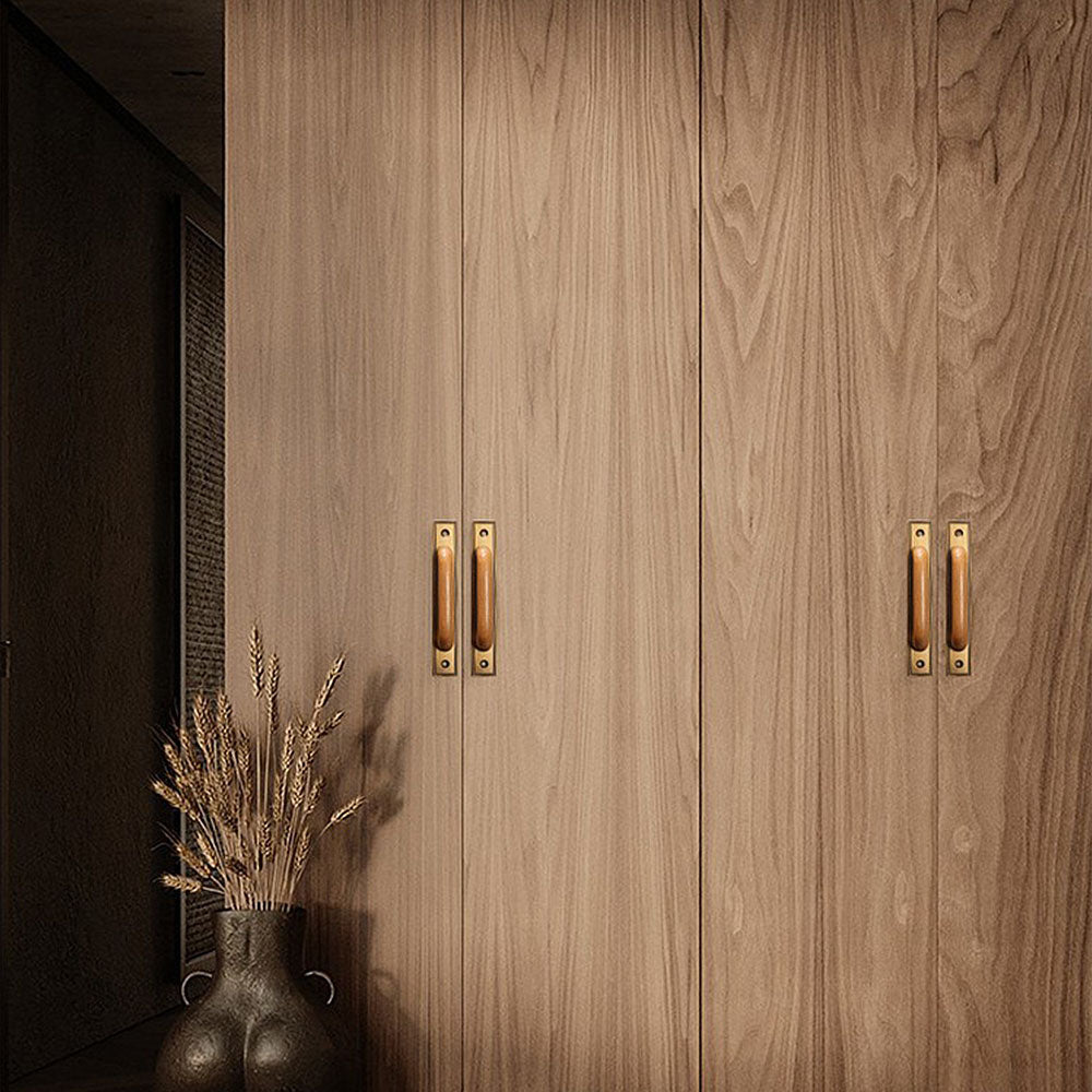 Wood cabinet pull with a rectangular metal backplate, shown at close range installed on cabinetry in context