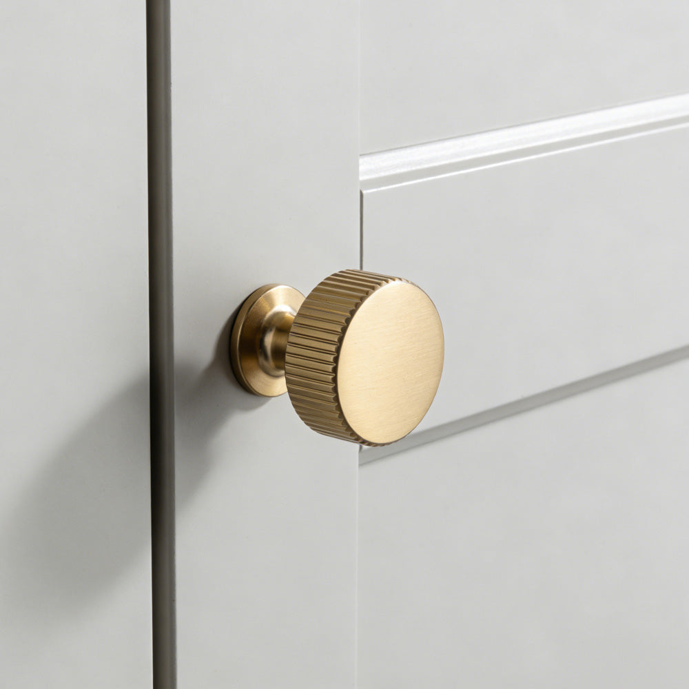 Matte gold fluted bar cabinet pull and round knob, displayed from the side with the finish and grip area visible