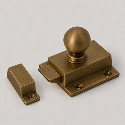An antique bronze door stopper with a round ball knob and a separate rectangular matching block, shown on a neutral light gray background.